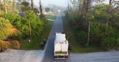 Çöp kamyonu Amerikan mahallesinin kaldırımından çöp kutusu yüklüyor.