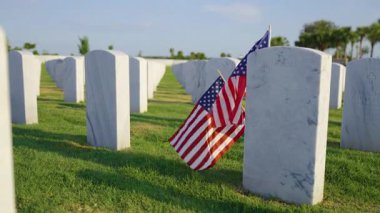 Beyaz mezar taşları ve yeşil çimlerin üzerinde Amerikan bayrağı olan Amerikan ulusal mezarlığı. Anma Günü konsepti
