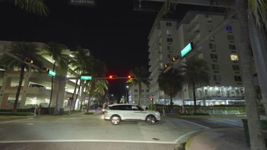 Gece Miami Beach, Florida 'da araba kullanırken görülmüş. Ulaşım ve trafik kavramı. Şehir caddesinde güney binaları arasında araç sürüyor.