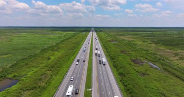 Florida sulak alanındaki otoyolun düz bölümü çimenli su kanalları ve sürüş trafiği ile çevrili.
