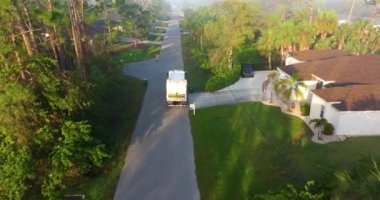 Yerleşim bölgesinde çöp temizleme. Atık kamyonlar banliyö sokaklarında sürerken çöpleri yüklüyorlar