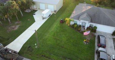 Sıfır dönüşlü çim biçme makinesi kullanan adam yazın Florida 'daki ev bahçesinde çim biçiyor.