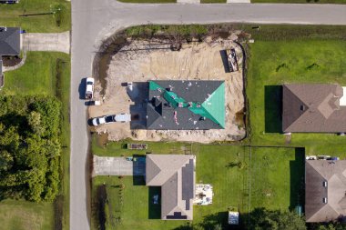 Construction workers installing asphalt shingles on residential home. New house rooftop being built