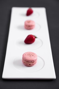 Macarons ve çilek bir plaka üzerinde
