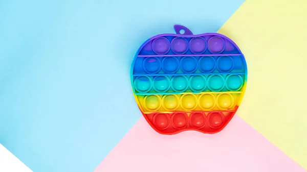 Simple Dimple touch multi-colored toy in the form of an apple on a colored background view from above Fotografia Stock