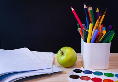 Okula dönüş kavramı, siyah karatahta okul malzemeleri açık defter, ön görünümde kopya alanı.