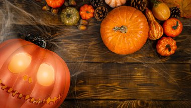 Balkabağı kafalı Jack-o-fener ve farklı küçük balkabakları, kozalaklar, meşe palamutları ve örümceklerle dolu ahşap arka planda fotokopi alanı manzaralı örümcekler, Cadılar Bayramı için arka plan