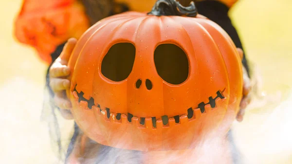 Κεφάλι κολοκύθας Jack-o-lantern στα χέρια ενός κοριτσιού σε ένα κοστούμι μάγισσα, γκρο-up φόντο για το Halloween — Φωτογραφία Αρχείου