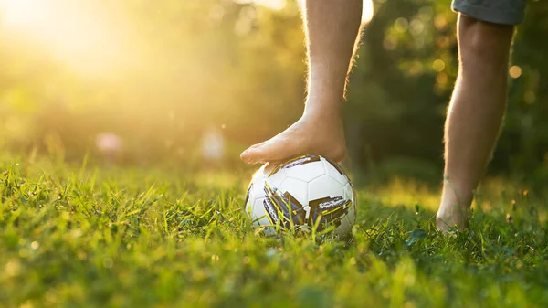 Mężczyzna stopa bez buty na piłce nożnej na trawiastym polu z słońce blask i przestrzeń kopia. — Zdjęcie stockowe