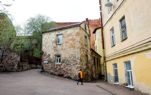VYBORG, RUSSIA - 15 Mayıs 2021: Sarı kapüşonlu bir adam Rusya 'daki en eski eve gidiyor - yurttaş evi - 16. yüzyılda inşa edildi..