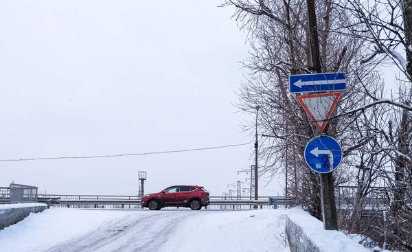 SAINT PETERBURG, RUSSIA - 17 HAZİRAN 2021: Karlı yol ve yol işaretleriyle kavşaklardan geçen kırmızı araba.