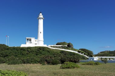Yeşil tepe üzerinde beyaz deniz feneri standı