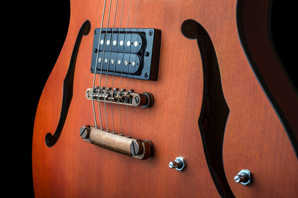 Hollow body electric guitar with humbuckers. Macro shot, black background, dark key