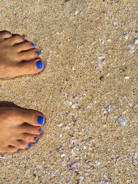 Füße mit blauer Pediküre am gelben Sandstrand — Stockfoto