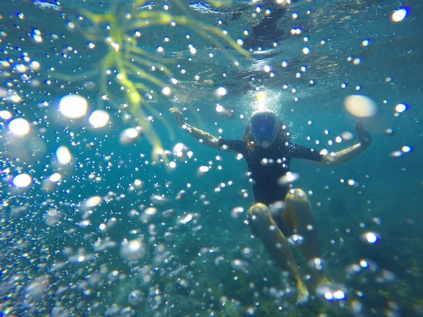 Chica de snorkel en traje de baño negro buceando en las burbujas en el mar — Foto de Stock