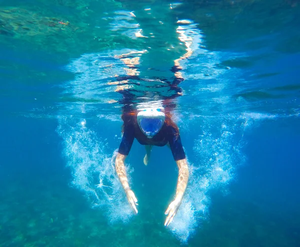 在全脸面具的蓝色大海中游泳的女孩 — 图库照片