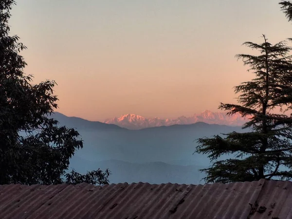 Himalaya 'nın nefes kesici silueti Landour' dan görüldüğü gibi, yuvarlanan çam ormanlarının yükselen beyaz tepelere yol verdiği yerde.