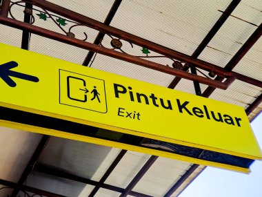 Sarı yön işareti üzerinde kalın siyah harflerle 'Pintu Keluar' ile 'Çıkış' ı gösterir.
