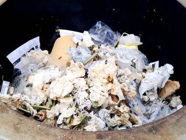 Dökülen atık kutusu atılmış kağıt, plastik torba ve organik maddeyle doludur..