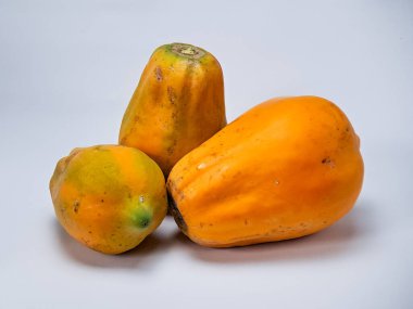 Turuncu ve yeşil derili üç olgun papaya tropikal ve canlı bir hayat sahnesi yaratır..