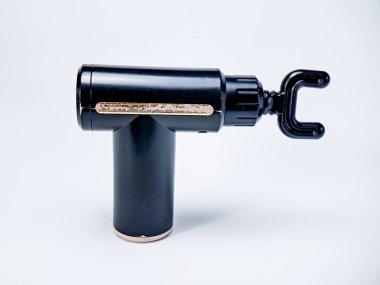 Kas ağrısı ve iyileşme terapisi için beyaz arka planda duran siyah bir masaj silahı.