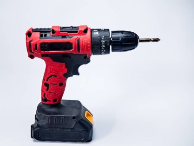 Kırmızı ve siyah elektrikli matkap, düz beyaz bir zemine karşı dik duruyor, alet delmek için..