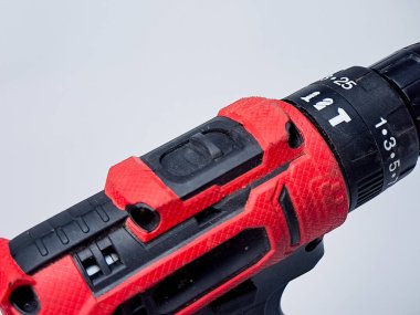 Modern bir kırmızı ve siyah matkap, tasarımı sergilenen, temiz beyaz bir zemine dayanır..