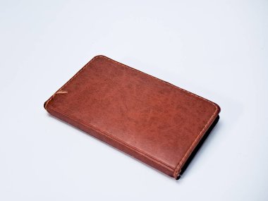 Elle dikilmiş kenarları olan eski bir deri günlük yumuşak ışıklandırmada nötr bir arka planda durur..