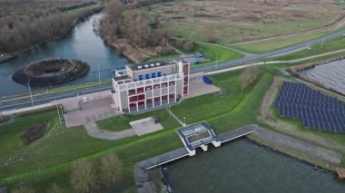 Hollanda 'da kanallar, kanallar ve güneş panelleriyle çevrili modern bir su pompalama istasyonunun insansız hava aracı görüntüsü, Hollanda' da sel kontrolü, su yönetimi ve kritik altyapı.