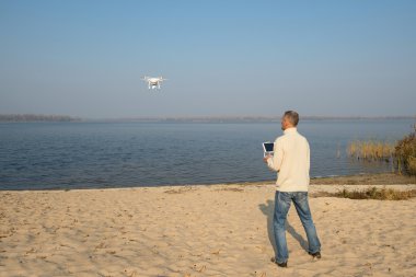 Bir adam güneşli bir sonbahar günü drone ile oynuyor.