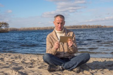 Büyülenmiş adam, rahat giyen, rahatlarken tabletini kullanarak