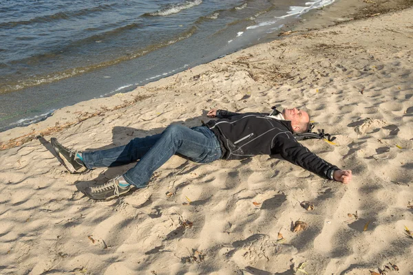 Szczęśliwy człowiek relaksując się na plaży, leżąc na piasku, uśmiechając się, Loo — Zdjęcie stockowe