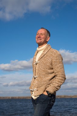 Adam gülümsüyor, raslantı giyen, deniz kenarı boyunca yürüyüş mutlu 