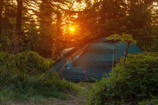 Tenda turística fica nos raios de pôr do sol no backgroun — Fotografia de Stock