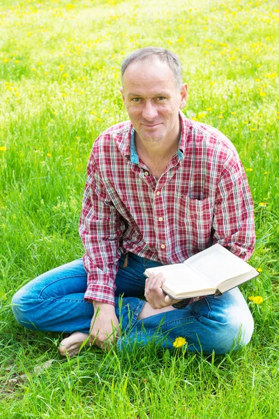 Parkta rahatlatıcı, bir kitap okumak ve gülümseyen, arayan bir adam 