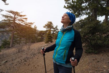 Mutlu bir kadın, bir çam ormanı içinde uzun yürüyüşe çıkan kimse 