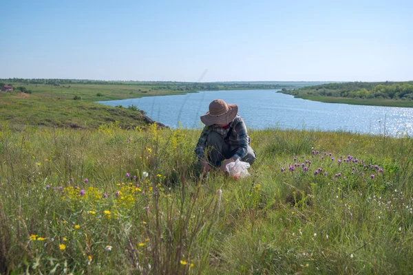 Woman in a straw hat, gathers herbs — Stock Photo, Image