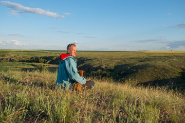 Neşeli uzun yürüyüşe çıkan kimse, adam bir köpekle oturur.