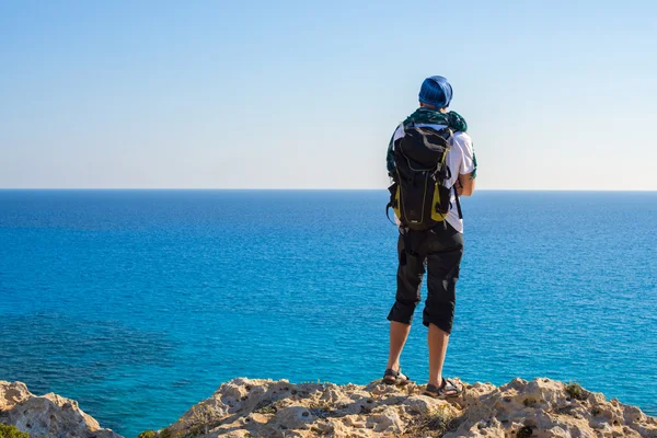 Caminhante com uma mochila na praia rochosa — Fotografia de Stock