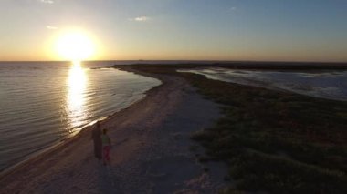 Çift sahilde günbatımı sırasında yürür..