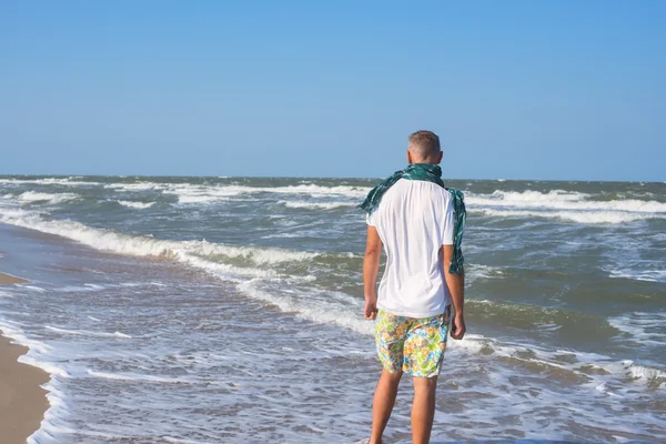 Aktiva mannen bär en scarf på stranden — Stockfoto