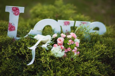 Yeşil dallarında pembe güller olan düğün buketi