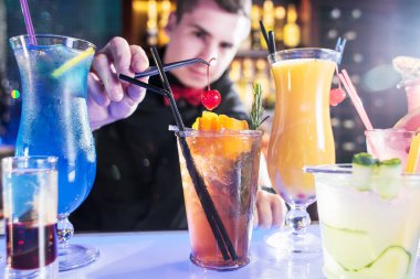 Barmen kokteylleri hazırlarken kiraz koyar.