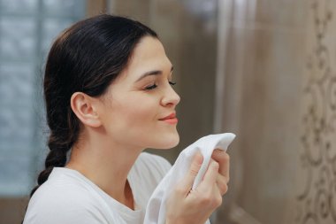 Genç bir kadın banyoda temiz çarşaf kokluyor.