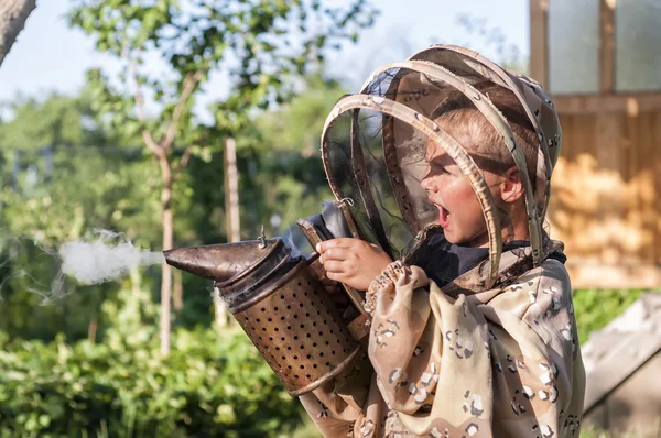 Jeune apiculteur garçon en utilisant un fumeur sur la cour d'abeille — Photo