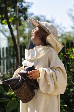 Sigara içen bir arı bahçede kullanarak genç arıcı çocuk