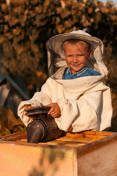 蜂の喫煙者の手でハイブ養蜂場で働いている若い男の子の養蜂家の肖像画 — ストック写真