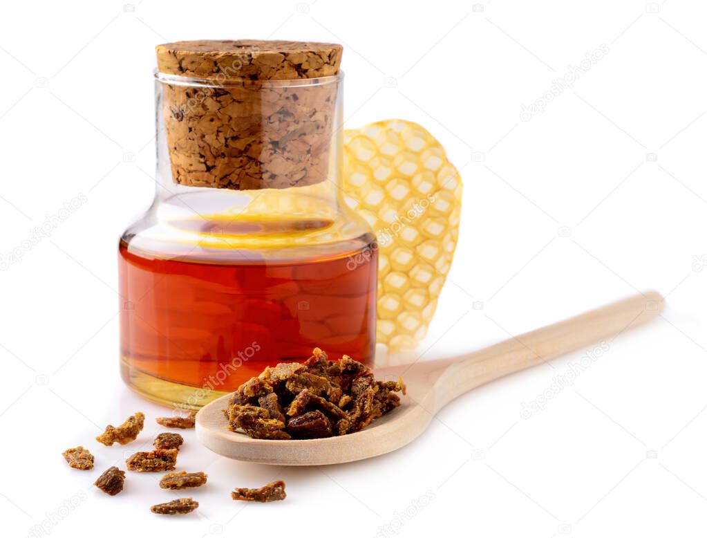 A bottle of propolis tincture and a wooden spoon of propolis granules. Medical preparations bee propolis. Apitherapy. Isolated on white background. Bee glue. Apitherapy