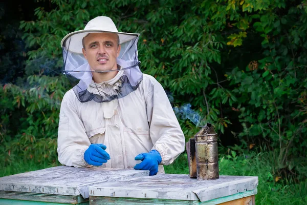 屋外で働くプロの養蜂家と養蜂に使用される保護スーツを身に着けています 養蜂家が蜂の巣から蜂蜜を収穫 — ストック写真