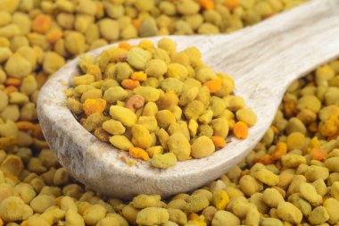 Çiçek arısı poleni ve tahta kaşık. Bağışıklık sistemini geliştirmek için doğal bir ilaç. Arıcılık ürünleri. Apioterapi